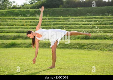 Frau mittleren Alters, die Yoga macht, die Half-Moon-Pose, Ardha Chandrasana, auf einer Wiese in einem Park im Sommer, Deutschland Stockfoto