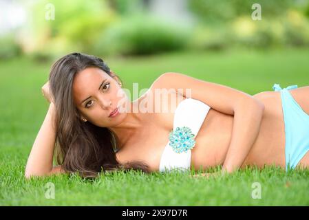 Junge attraktive Frau, die auf einer Wiese in einem Freiluftbad liegt Stockfoto