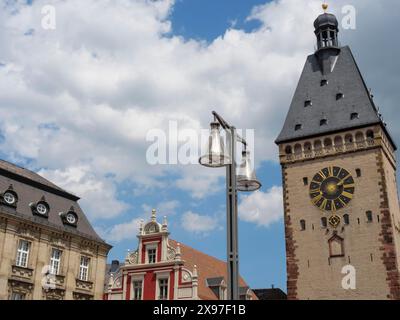 Ein Uhrenturm und ein benachbartes historisches Gebäude, ergänzt durch eine moderne Laterne vor einem bewölkten Himmel, Turm mit Uhrenturm vor dem historischen Stockfoto