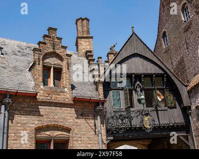 Detaillierter Blick auf historische Backsteingebäude mit gotischen Fenstern in einer Gasse, historische Hausfassaden in einer mittelalterlichen Stadt am Fluss, Brügge, Belgien Stockfoto