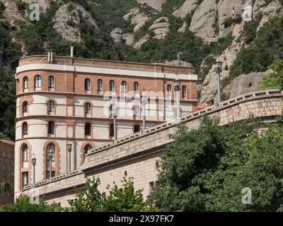 Ein altes, mehrstöckiges Gebäude mit Bögen, umgeben von Felsen und Bäumen unter sonnigem Himmel, Kloster in felsigen Bergen, Barcelona, Spanien Stockfoto