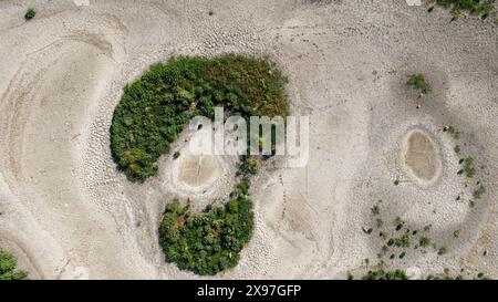 Die letzten grünen Pflanzen in einem trocknenden See. Ein Blick auf gerissenen Boden. Stockfoto