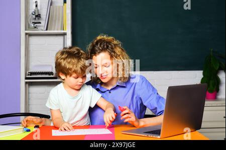 Lehrer, der dem Jungen beim Zeichnen, Schreiben oder Lernen hilft. Schulungsprozess. Mutter bringt dem kleinen Sohn Lesen und Schreiben bei. Glückliche Familie Stockfoto