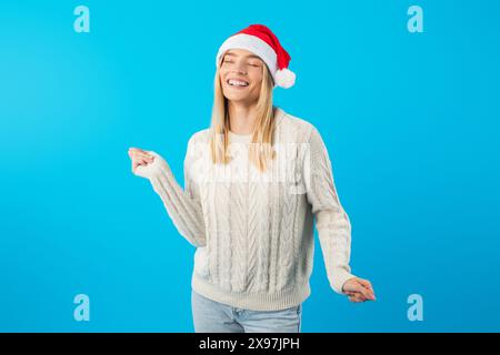 Fröhliche junge Frau in Santa hat feiert Weihnachten gegen Blau Stockfoto