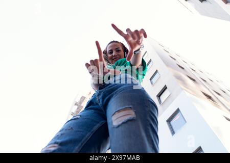 Junge, fröhliche Frau, die in der Stadt tanzt und Kopfhörer trägt Stockfoto