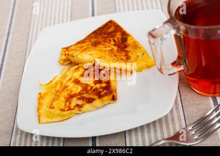 Es gibt Pfannkuchen mit Apfelfüllung, die in Dreieck auf dem Teller gerollt sind Stockfoto