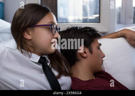 Teenager-Paar sitzt eng zusammen, beide scheinen besorgt zu sein. Das Mädchen sieht nachdenklich aus, während der Junge sich auf ihre Schulter lehnt und einen Moment der Rela reflektiert Stockfoto