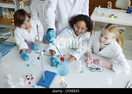 Hochwinkelansicht von nicht erkennbaren Lehrern und multiethnischen Kindern, die Experimente im Chemiekurs machen Stockfoto