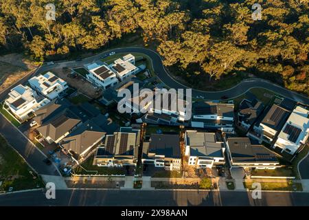 Letzter Blick auf neu gebaute moderne Häuser in den äußeren Vororten von Sydney, Australien. Im Hintergrund sind heimische Eukalyptusbäume (der Busch) zu sehen. Stockfoto