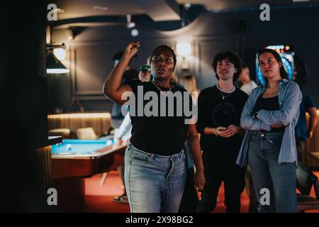 Vielfältige Gruppe junger Freunde, die ein lustiges Dartspiel in einer stilvollen Bar genießen Stockfoto