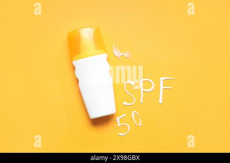 Flasche Sonnencreme und Text SPF 50, geschrieben mit Creme auf farbigem Hintergrund Stockfoto