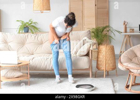 Junge afroamerikanische Frau, die zu Hause enge Hosen anziehen will. Diätkonzept Stockfoto