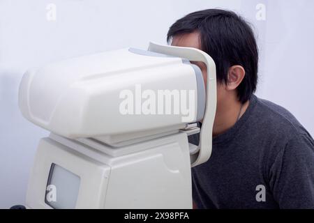 Junger, gutaussehender Asiate macht eine Augenuntersuchung mit einem optischen Augen-Testgerät Stockfoto