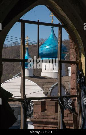 Blick auf die Zwiebelkuppel der Russisch-orthodoxen katholischen Kirche St. Marias durch ein weiteres verlassenes Kirchenfenster. Stockfoto