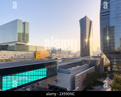 Sonnenuntergang über Abu Dhabis Skyline von Al Maryah Island, Vereinigte Arabische Emirate. Die leuchtenden Farben der untergehenden Sonne erhellen das moderne Archi Stockfoto