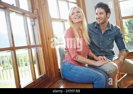Paare, zusammen und glücklich auf der Fensterbank für Outdoor Bonding, Lächeln oder Leute umarmen sich in der Wohnung für Unterstützung. Heim, Engagement für die Ehe und Entspannung Stockfoto