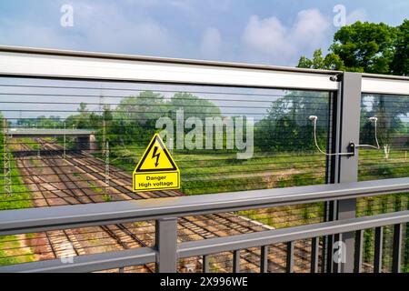 Warnschild für Lebensgefahr durch Hochspannung am Geländer einer Eisenbahnbrücke. Stockfoto