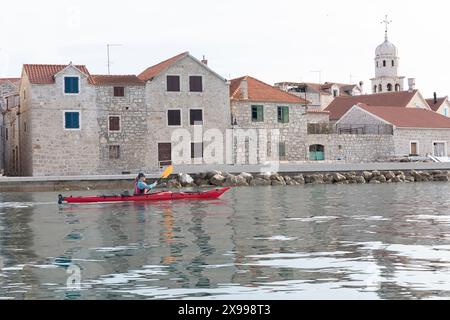 Touristische Kajakfahrer fahren vorbei an dem wunderschönen alten Teil eines Dorfes Prvic Sepurine auf der Insel Prvic im Sibenik Archipel in Kroatien Stockfoto