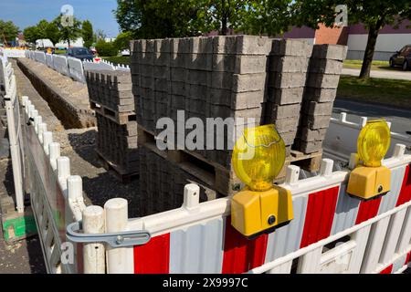Pflasterplatten, die auf Holzpaletten gestapelt und von einem Kunststoffzaun umgeben sind. Nahaufnahme. Stockfoto