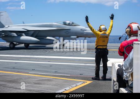 Philippine Sea, Usa. Mai 2024. Ein Flugdirektor der US Navy signalisiert dem Piloten eines F/A-18E Super Hornet Kampfflugzeugs, das an der Dambusters of Strike Fighter Squadron 195 befestigt ist, vom Flugdeck des Nimitz-Klasse-Flugzeugträgers USS Ronald Reagan zu starten, der am 29. Mai 2024 in der Philippinischen See unterwegs ist. Foto: MC2 Evan Mueller/US Navy Photo/Alamy Live News Stockfoto