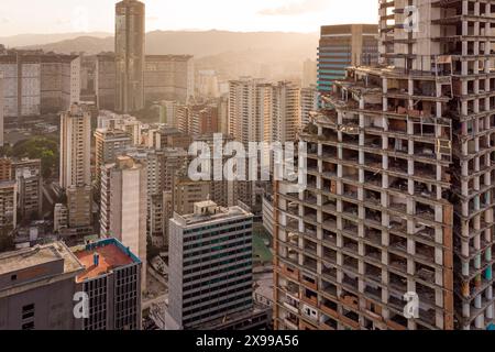 Blick aus der Vogelperspektive auf Caracas bei Sonnenuntergang mit dem David Tower Wahrzeichen Wolkenkratzer und Slums sichtbar. Drohnenaufnahme der venezolanischen Hauptstadt bei Sonnenuntergang. Konzept o Stockfoto