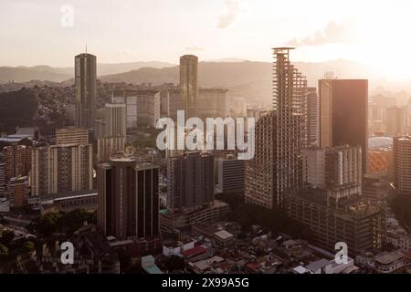 Blick aus der Vogelperspektive auf Caracas bei Sonnenuntergang mit dem David Tower Wahrzeichen Wolkenkratzer und Slums sichtbar. Drohnenaufnahme der venezolanischen Hauptstadt bei Sonnenuntergang. Konzept o Stockfoto