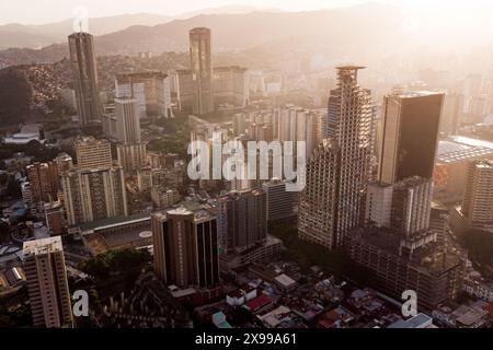 Blick aus der Vogelperspektive auf Caracas bei Sonnenuntergang mit dem David Tower Wahrzeichen Wolkenkratzer und Slums sichtbar. Drohnenaufnahme der venezolanischen Hauptstadt bei Sonnenuntergang. Konzept o Stockfoto