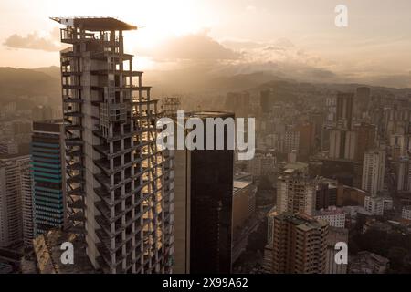 Blick aus der Vogelperspektive auf Caracas bei Sonnenuntergang mit dem David Tower Wahrzeichen Wolkenkratzer und Slums sichtbar. Drohnenaufnahme der venezolanischen Hauptstadt bei Sonnenuntergang. Konzept o Stockfoto