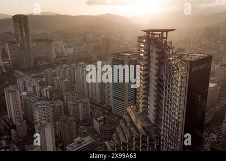 Blick aus der Vogelperspektive auf Caracas bei Sonnenuntergang mit dem David Tower Wahrzeichen Wolkenkratzer und Slums sichtbar. Drohnenaufnahme der venezolanischen Hauptstadt bei Sonnenuntergang. Konzept o Stockfoto