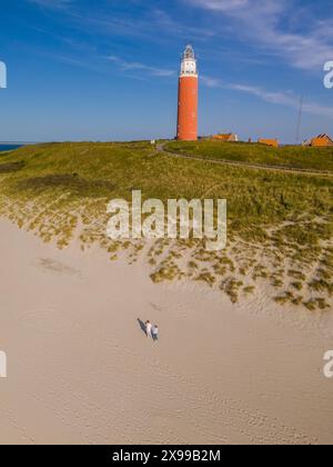 Ein Blick von oben auf einen majestätischen Leuchtturm, der hoch auf einem Sandstrand steht und sein Licht über die weite Küste von Texel, Niederlande, wirft. Stockfoto
