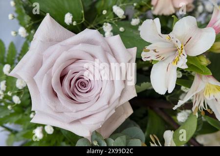 Tischdekor für eine formelle Veranstaltung oder eine Hochzeit, Blumenmotiv mit großen lila-rosa Rosen und Lilien, umgeben von Atem und Laub des Babys Stockfoto