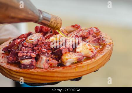 Olivenöl auf einer Portion Tintenfisch, zubereitet im traditionellen Pulpo a feira Stil. Galicien, Spanien Stockfoto