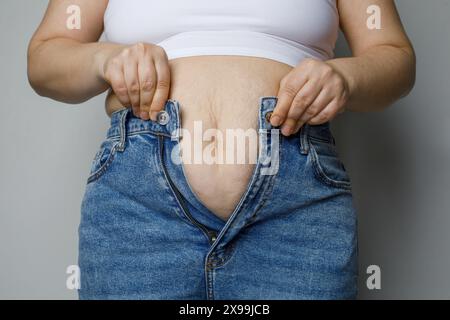 Eine Frau, die versucht, ihre Jeanshosen hochzuziehen, Diätkonzept Stockfoto