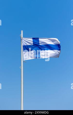 Finnlands Flagge am Pfosten, die im windwolkenlosen blauen Himmel winkt Stockfoto
