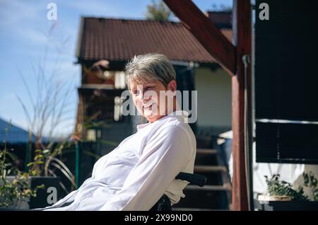 Eine ältere Frau genießt einen Moment der Ruhe im Rollstuhl mit Blick auf die Berge Stockfoto