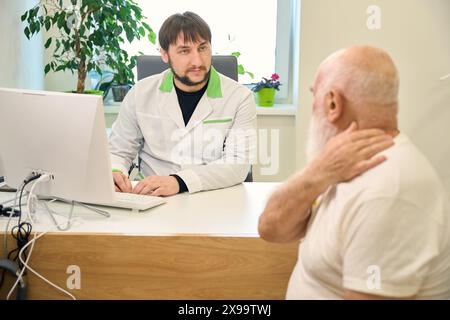 Der Patient kommuniziert mit dem Arzt, während er in der Arztpraxis sitzt Stockfoto