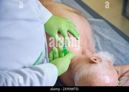 Der Arzt macht einen Bluttest von einem lügenden Patienten Stockfoto