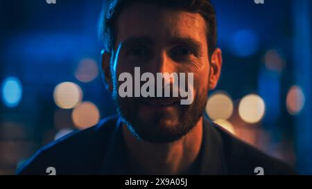 Porträt eines hübschen Mannes, der zu Hause auf einer Couch verweilt und mit Fernbedienung Fernsehsender im stilvollen Loft Apartment schaltet. Junger Mann, der den Film-Streaming-Service aktiviert und sich entspannt. Stockfoto