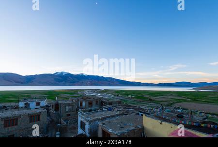 Ackerland und Weiler mit Gebetsfahnen hängen von den Dächern, neben dem hohen TSO Moriri (See Moriri) auf dem Changthang-Plateau, Ladakh, Indien Stockfoto