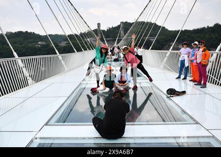 Zhangjiajie. Mai 2024. Südkoreanische Touristen machen Fotos an einer Brücke mit Glasboden am Zhangjiajie Grand Canyon in der zentralen chinesischen Provinz Hunan, 23. Mai 2024. Im ersten Quartal 2024 verzeichnete Zhangjiajie 105.100 südkoreanische Touristenreisen, was einem Anstieg von 27,07 Prozent gegenüber dem gleichen Zeitraum im Jahr 2019 entspricht. Auf Zhangjiajie entfallen 40,23 Prozent der Gesamtzahl der Touristen, die nach Zhangjiajie einreisen. Derzeit gibt es Direktflüge von fünf Städten in Südkorea nach Zhangjiajie, darunter Seoul und Busan, mit insgesamt 52 Flügen pro Woche. Quelle: Chen Zhenhai/Xinhua/Alamy Live News Stockfoto