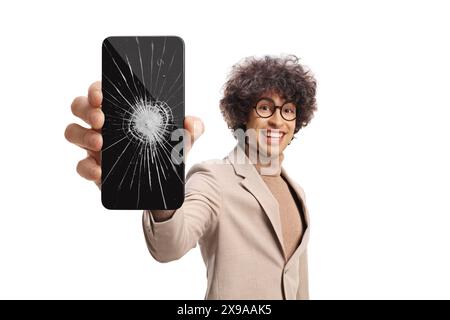 Junger Mann, der ein Handy mit zerbrochenem Glas auf weißem Hintergrund hält Stockfoto