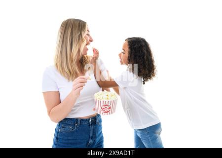 Frau in leichten Kleidern hat Spaß mit süßem Mädchen 5 Jahre alt, das Popcorn isst Stockfoto