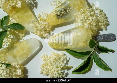 Gefrorene weiße Holunderblüten in Wasser in Form von Eis auf einem weißen Tisch. Stockfoto