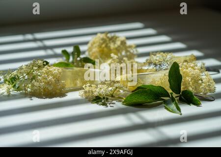Gefrorene weiße Holunderblüten in Wasser in Form von Eis auf einem weißen Tisch. Stockfoto