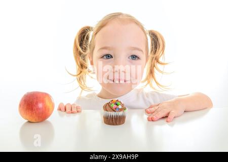 Kind Mädchen mit Cupcake und Apfel auf weißem Hintergrund Stockfoto