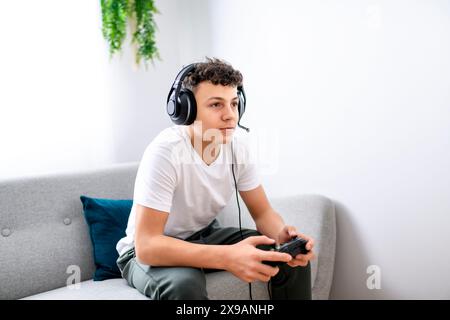 Porträt eines Teenagers, der im Urlaub Videospiele im fernsehen spielt, sitzt zu Hause auf der gemütlichen Couch Stockfoto