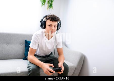 Porträt eines Teenagers, der im Urlaub Videospiele im fernsehen spielt, sitzt zu Hause auf der gemütlichen Couch Stockfoto