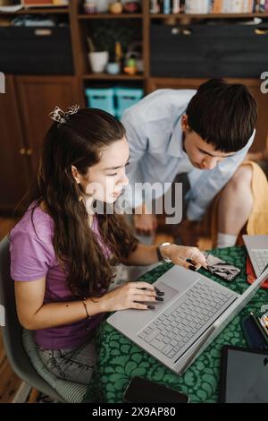 Hochwinkelansicht von männlichen und weiblichen Geschwistern, die während des Studiums zu Hause über einen Laptop diskutieren Stockfoto