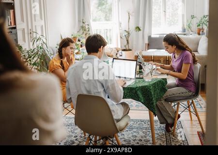 Geschwister lernen zusammen, während sie zu Hause auf dem Tisch sitzen Stockfoto