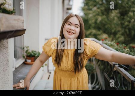 Lächelnde Frau mit Down-Syndrom, die auf dem Balkon steht Stockfoto